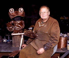 Hercule, the copper frog, reading The Hobbit to Chris, who loves the scorched leather look. Hercule now lives in Hinckley, Ohio.